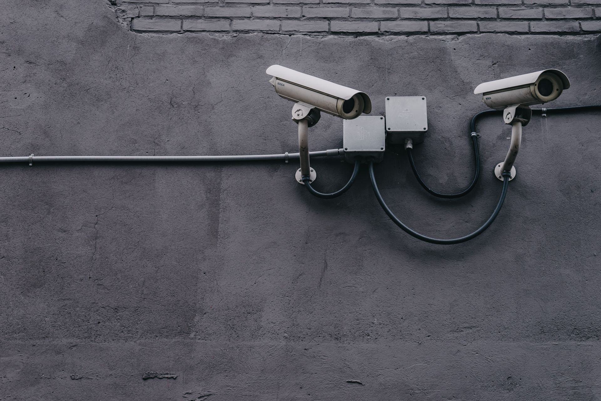 Two CCTV cameras mounted on a grey wall